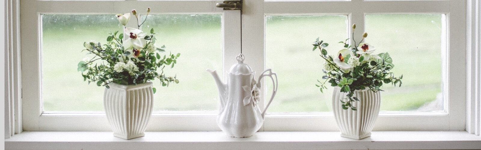 two flower pots and a kettle in front of a window